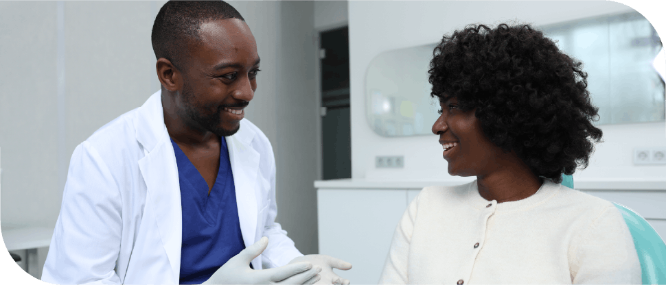 African dentist talking to female patient