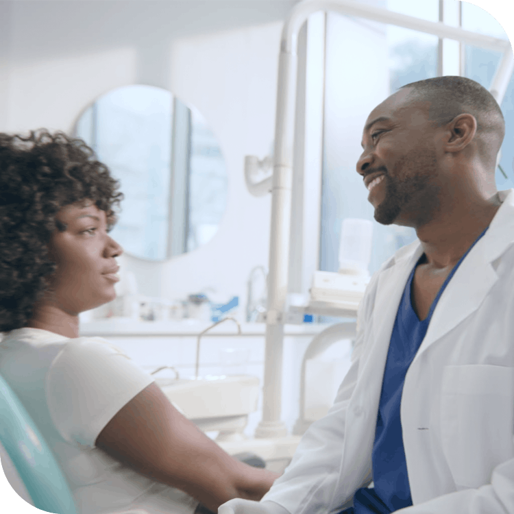 African dentist talking to female patient