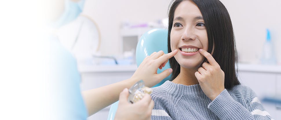 Woman smiling, pointing to teeth