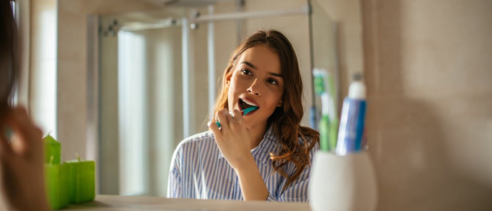 Girl brushing teeth in front of the mirror