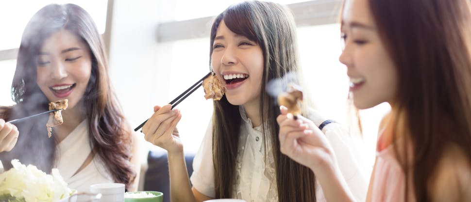 Three women laughing and eating