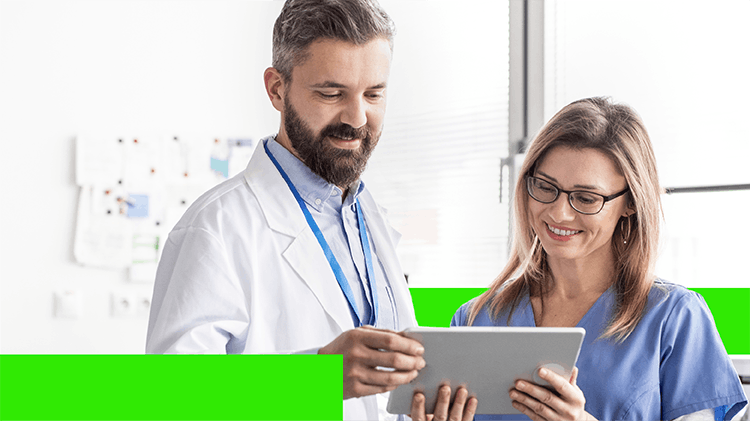 Dentist and dental assistant review a tablet together, smiling