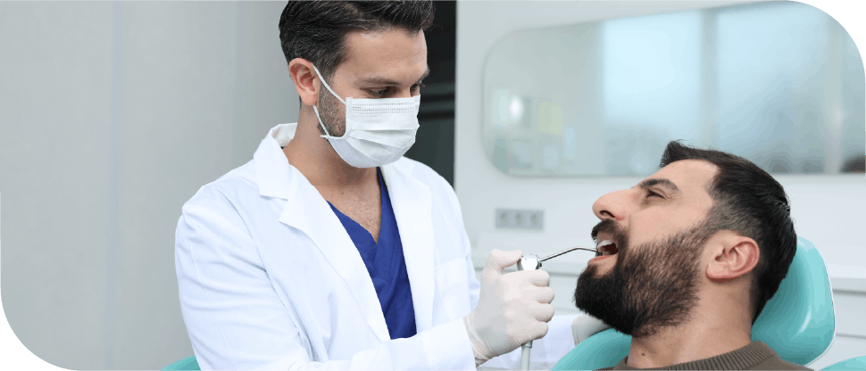 Dentist with air probe checking patient ‘s teeth (Pakistan male)