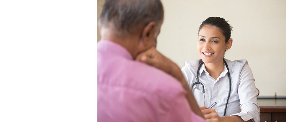 A doctor wearing a stethoscope around her neck talking to an older man