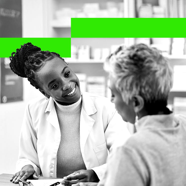  A young female pharmacist smiles while talking to an older female patient