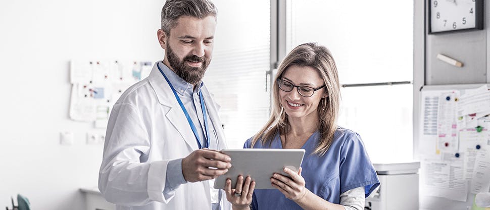 Dental professionals smiling while looking at a tablet.