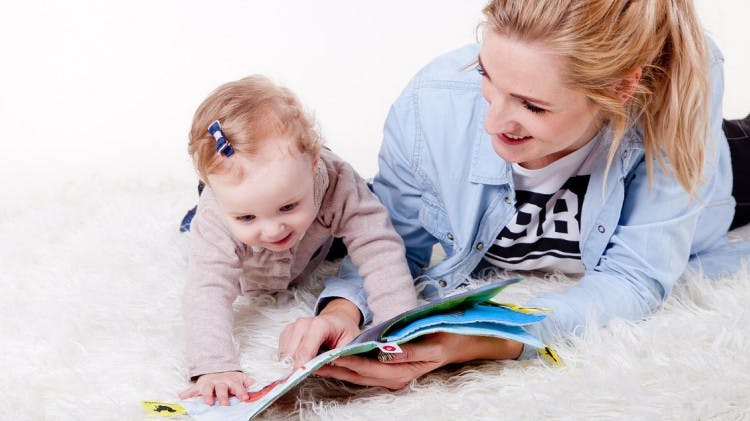 Mother and young child reading a book on the rug