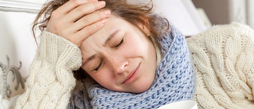 Woman lying on the bed, holding her forehead because of headache