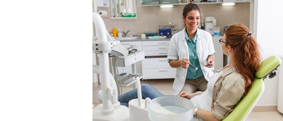 A dentist holdering a dental mirror talking to a lady