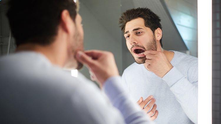 An image of man looking at gums in mirror