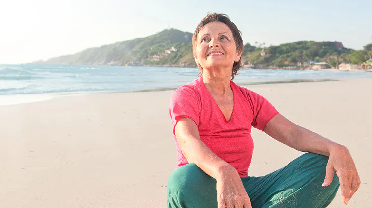Older woman sitting cross-legged on beach