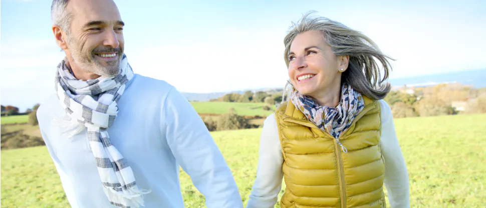 Older man and woman holding hands while walking