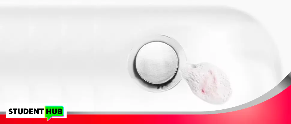 Image of a sink plug hole, with toothpaste that has been spat into it. There is blood visible in the toothpaste