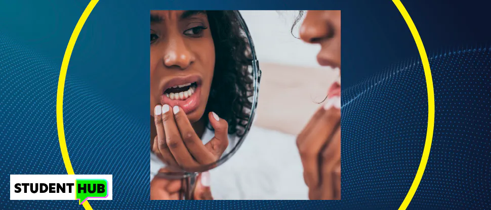 Image of a young woman with dental pain, holding the side of her face and looking in a mirror