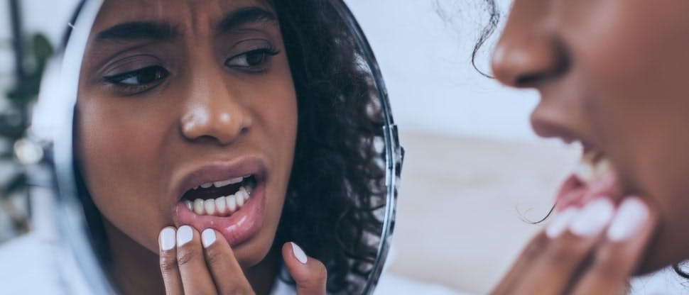 Woman with dental pain looks at her teeth in a mirror