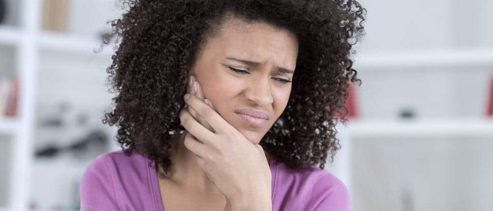 Woman with wisdom tooth pain touches jaw