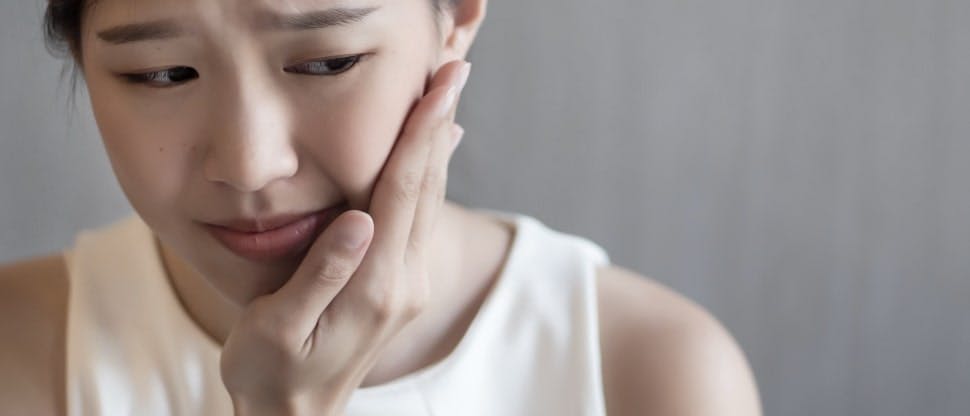 Woman with dental pain touches her jaw