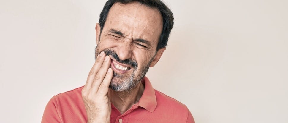 Man grimaces while experiencing dental pain