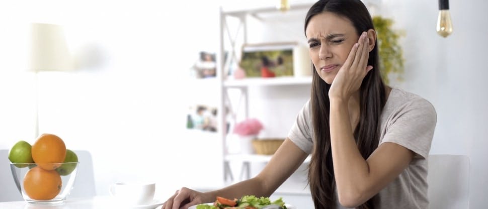 Woman with dental pain while eating salad