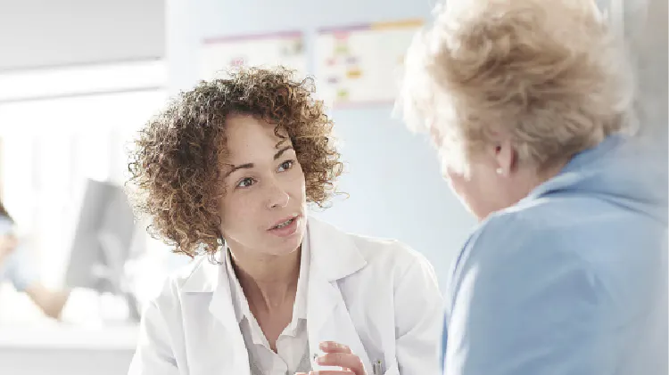 A doctor and a person seated in a medical office having a conversation facing each other.