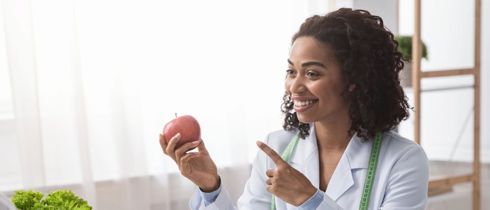 Healthcare professional holding an apple while discussing the relevance of oral hygiene to nutrition