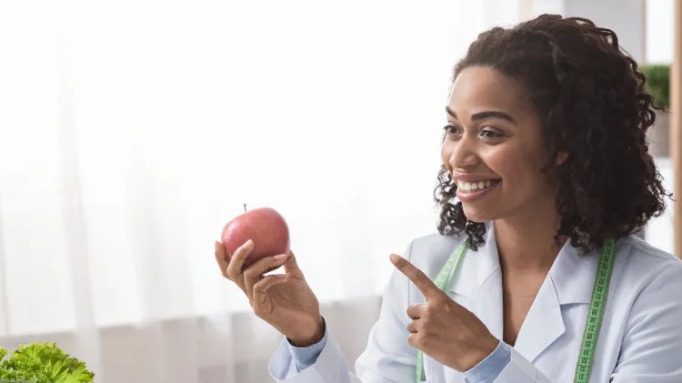 Healthcare professional holding an apple while discussing the relevance of oral hygiene to nutrition