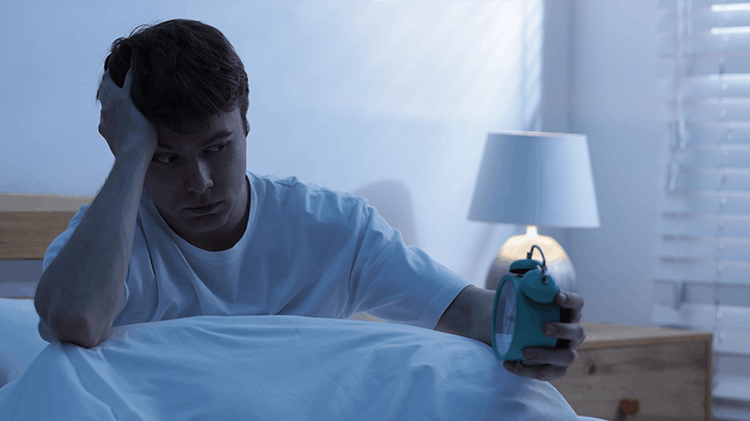 Man in bed with pain looking at a clock
