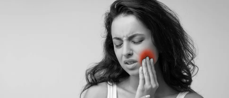 Young woman holds a hand to her cheek, wondering how to stop tooth pain