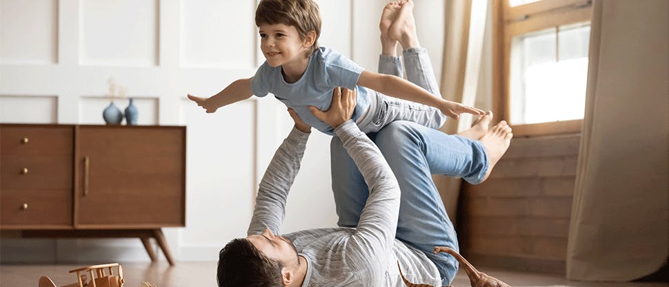 Father lying on the ground lifts his son in the air