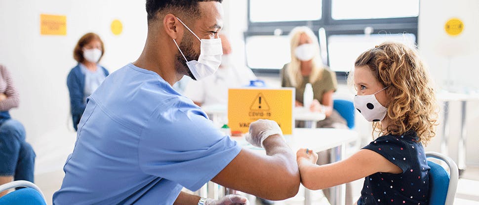 Masked doctor greets young child