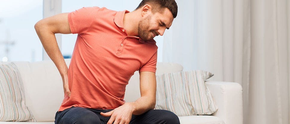 Man on couch suffering from back pain