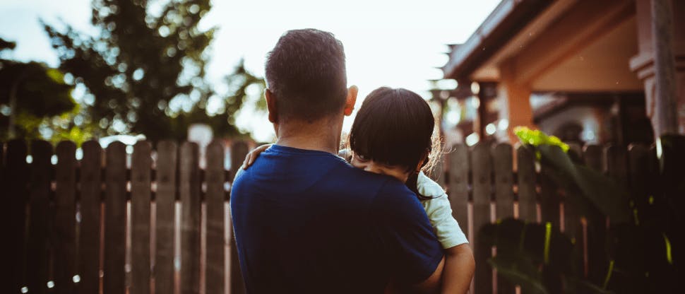 Man holding his young child in backyard 