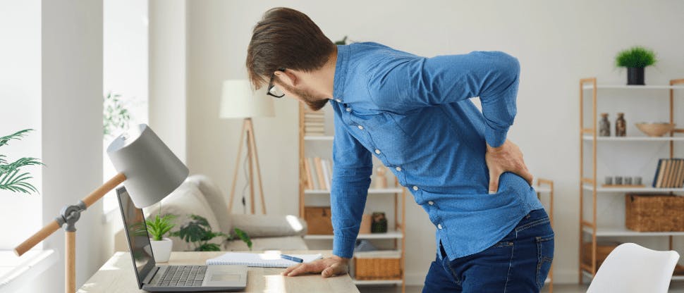 Man experiencing back pain after working at his desk  