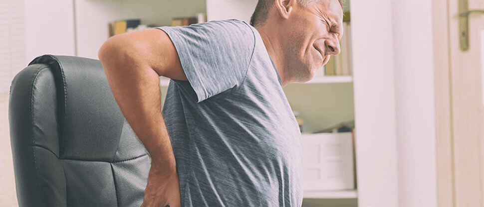 Man suffering from lower back pain in office chair