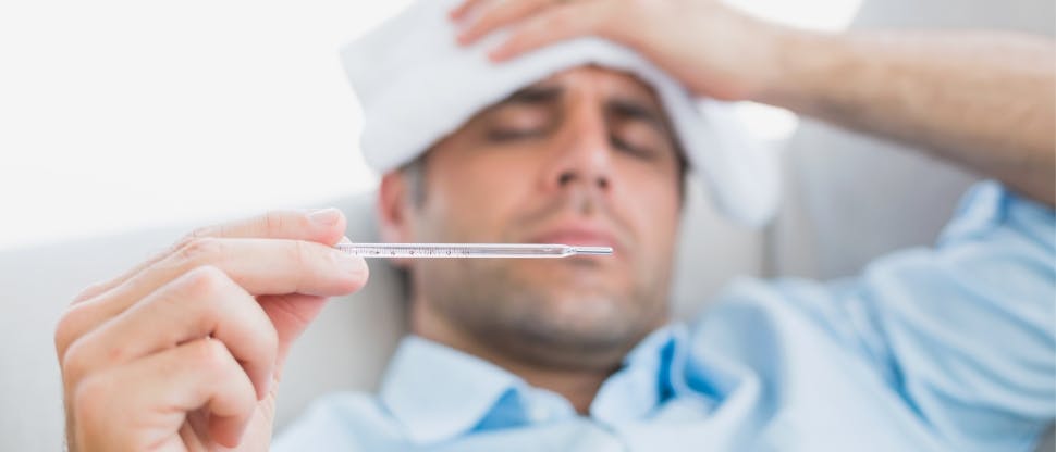 Man with fever holding thermometer