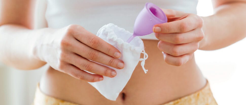 Woman holding menstrual cup and bag