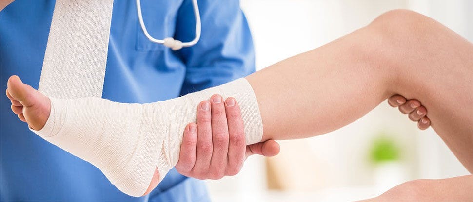 Close-up of male doctor bandaging foot of female patient at doctor's office