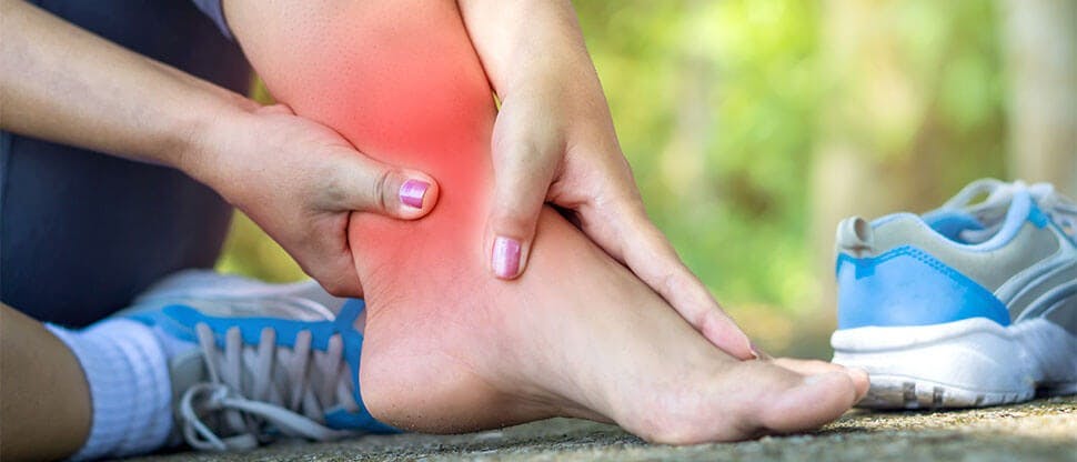 Woman massaging painful ankle injury