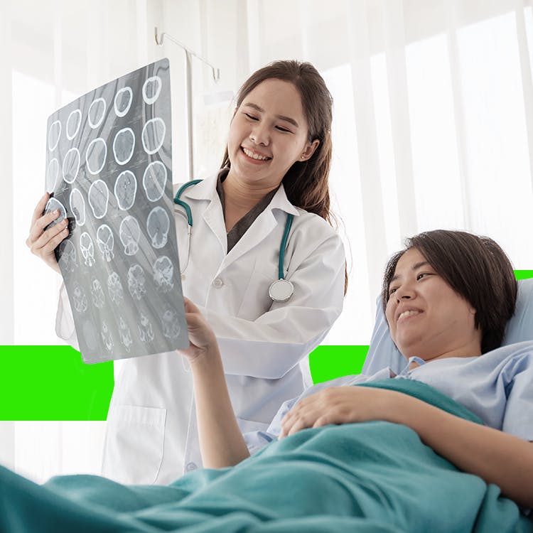 Doctor holding a brain scan X-ray while a patient lies in a hospital bed during a neurological health consultation.