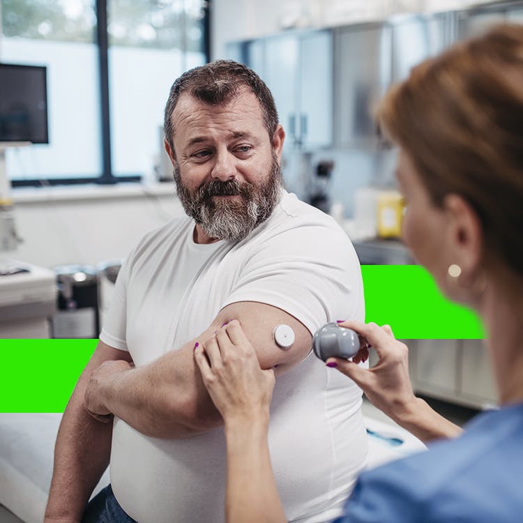A man pricking his finger for a glucose test, with glucometer nearby