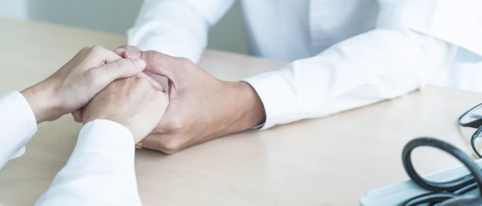 Healthcare professional offering comfort and support to an aging person by gently holding their hands