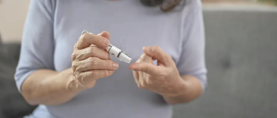 Woman using a blood glucose testing device to check blood sugar at home