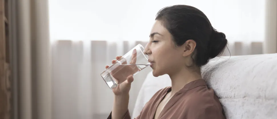A woman with dry mouth drinking water from a glass