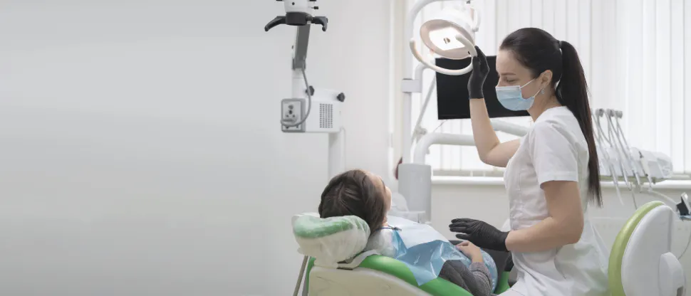 Patient with sensory issues wears sunglasses and watches a hygienist brush his teeth in a mirror to mitigate anxiety 