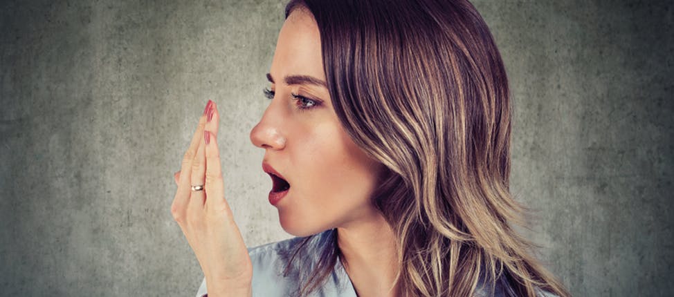 Woman using her hand to test her breath