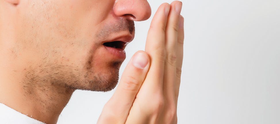 Young man testing his breath with his hand