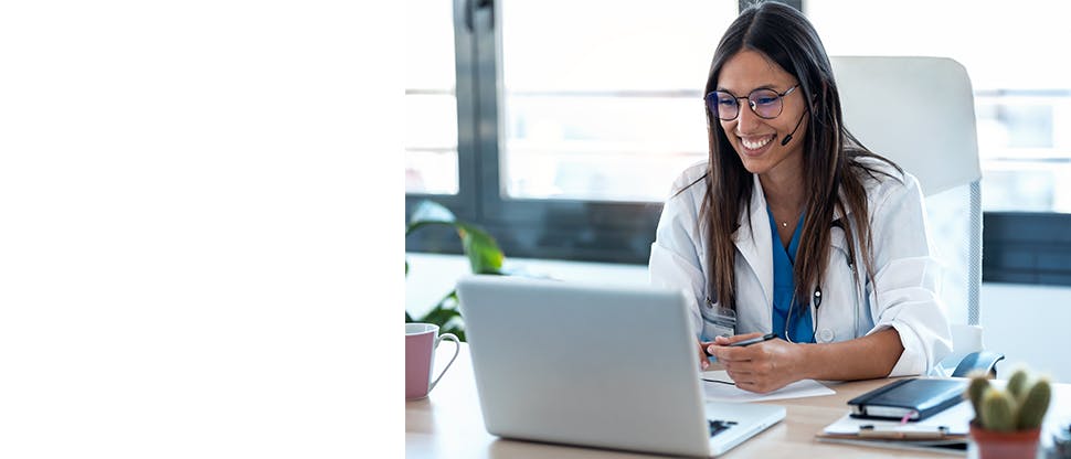 A doctor wearing headphone taking an online call on a laptop