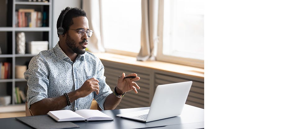 A man wearing headphones taking an online call on a laptop