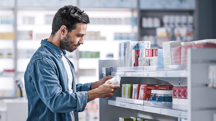 A man selects an item from a shelf in a pharmacy.