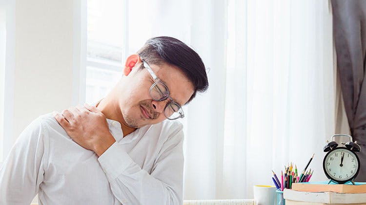 Man in pain at desk holding his neck